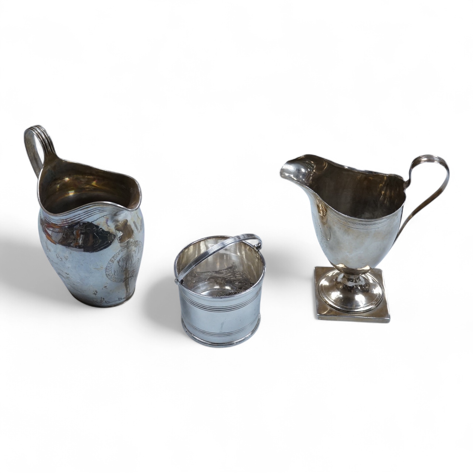 A George III silver cream jug, of oval form, London, 1801, 11cm, a George III silver helmet shaped cream jug, London, 1793, a George III small silver sugar pail, London, 1799 and a George V silver 'whisky' label, 8.4oz.